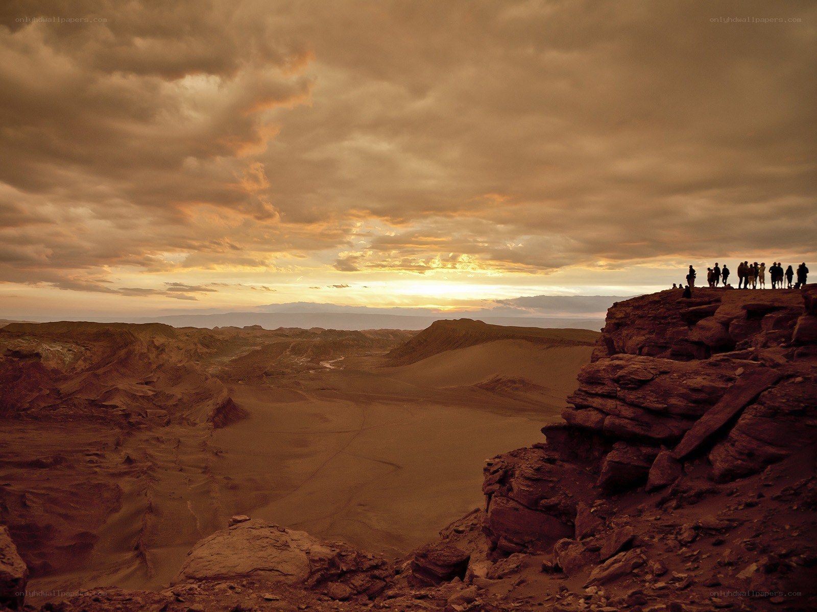 People on a cliff at sunset