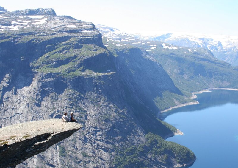 People on a cliff overlooking a fjord