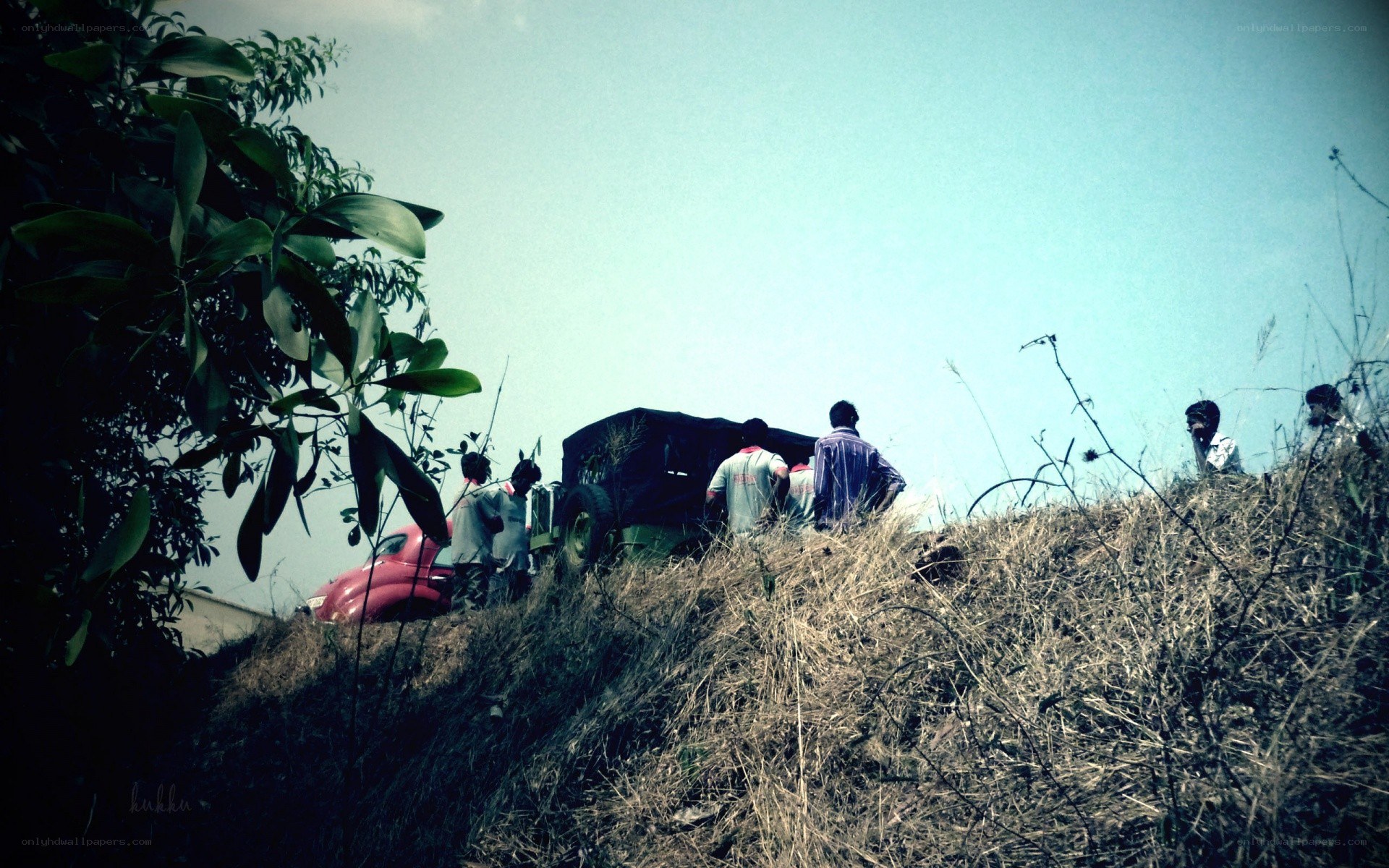 People on a hillside with vehicles