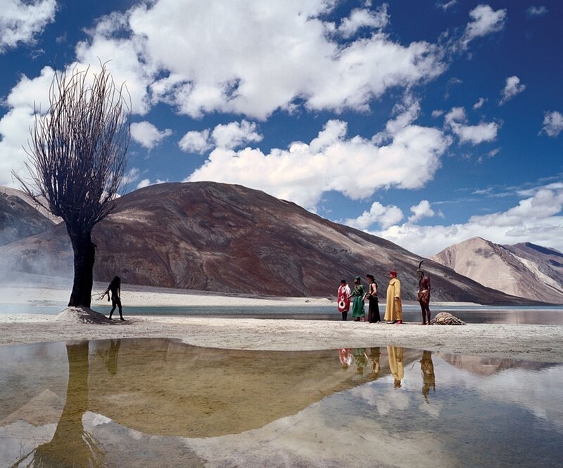 People on a lakeshore with mountains