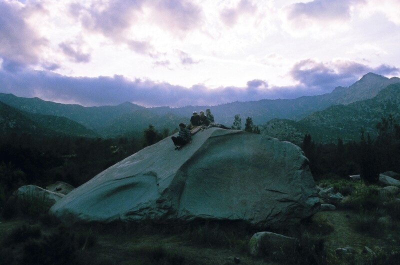 People on a large rock at dusk