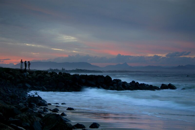 People on a rocky shore at sunset