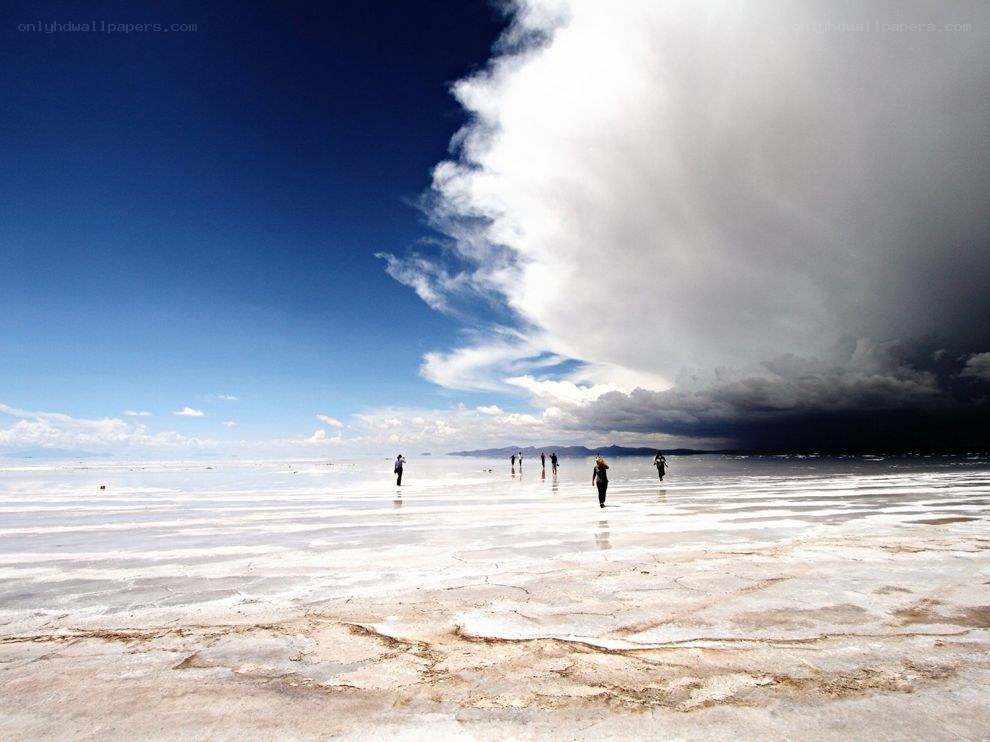 People on a salt flat under storm clouds