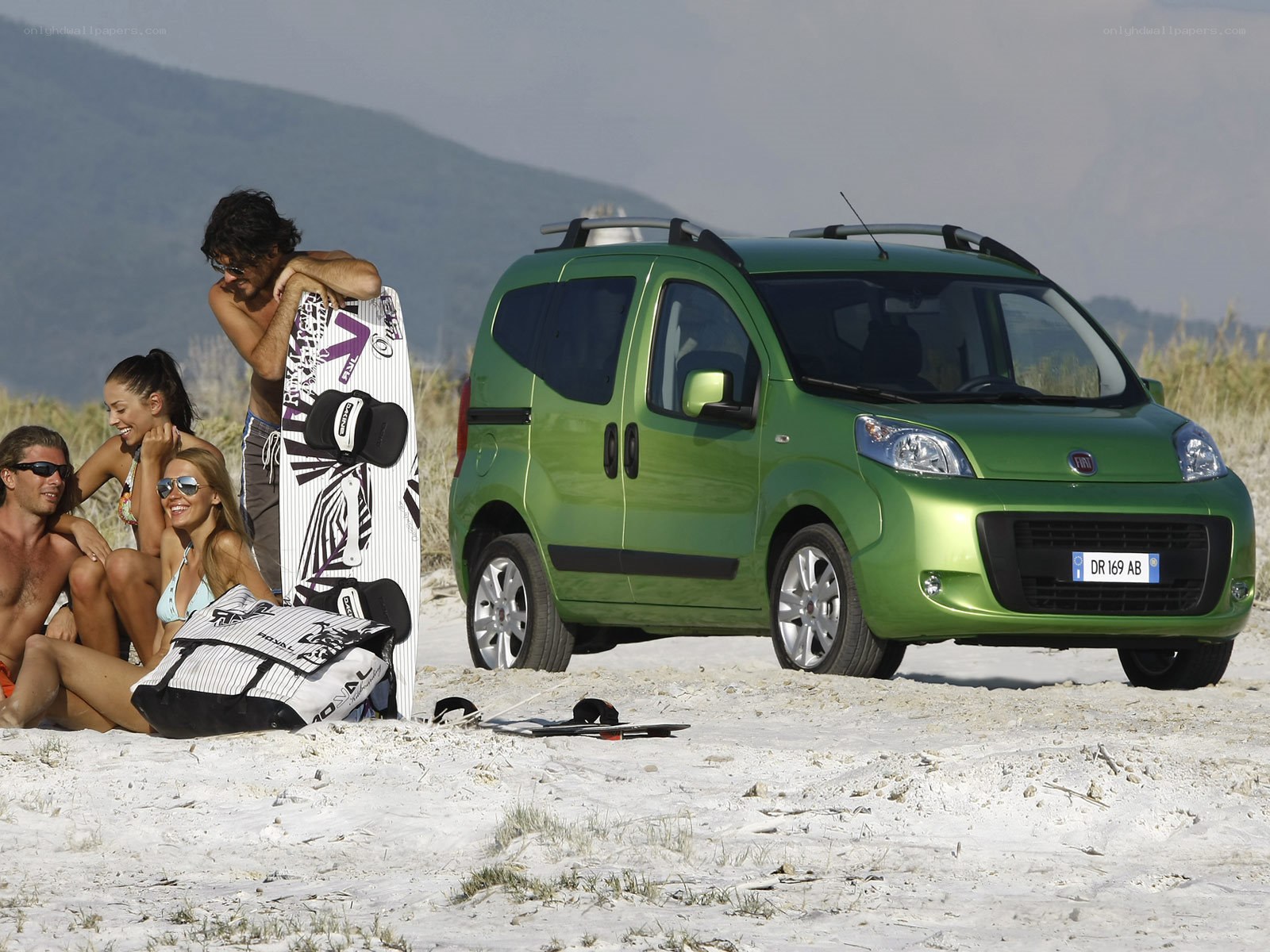 People on beach with green car