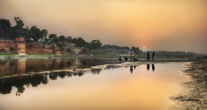 People on Riverbank at Sunset