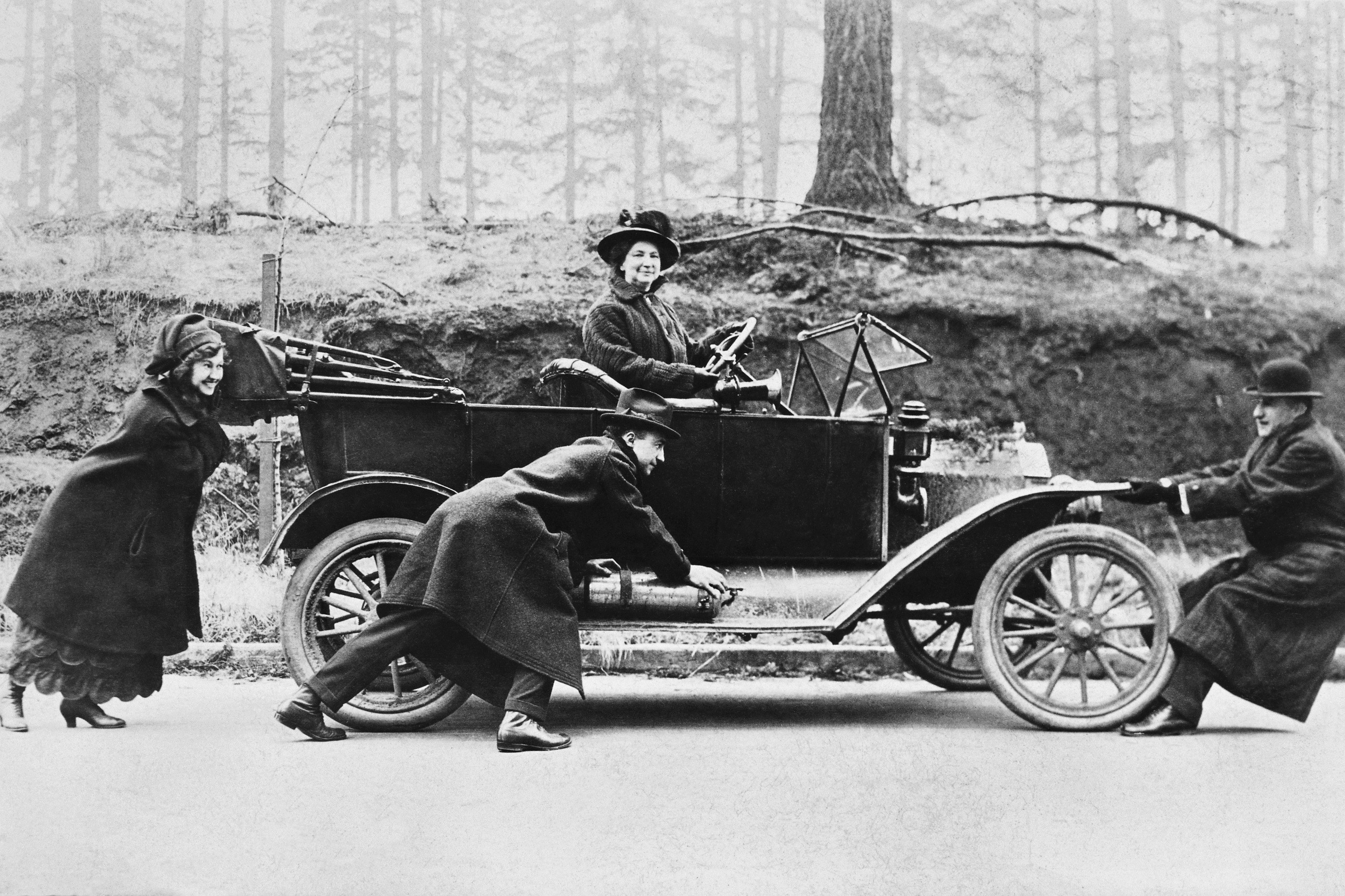 People pushing a vintage car