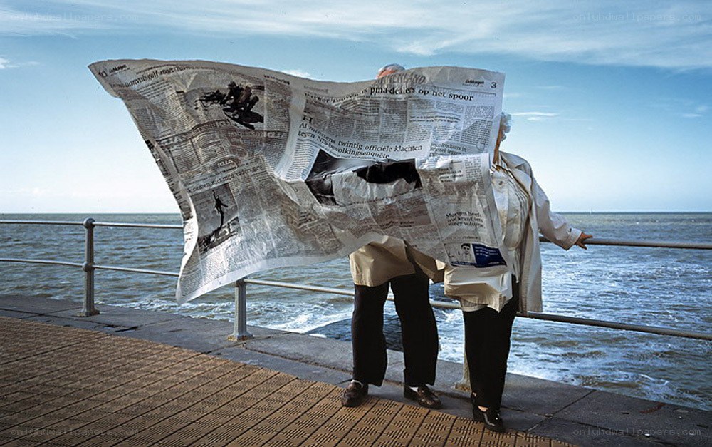 People reading newspaper on pier