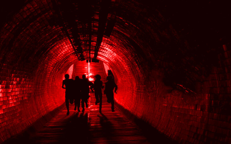 People running in red-lit tunnel