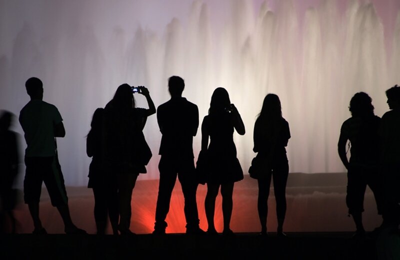 People silhouetted by a fountain