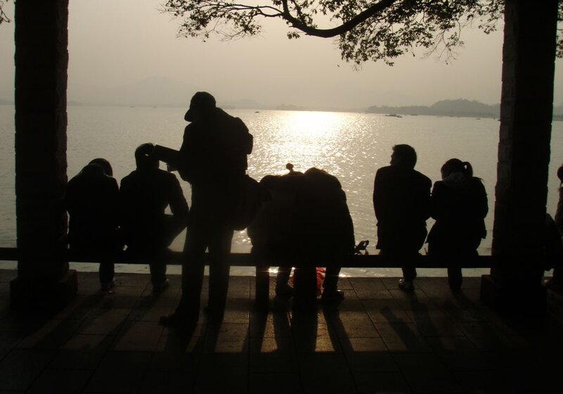 People silhouetted by lake sunset