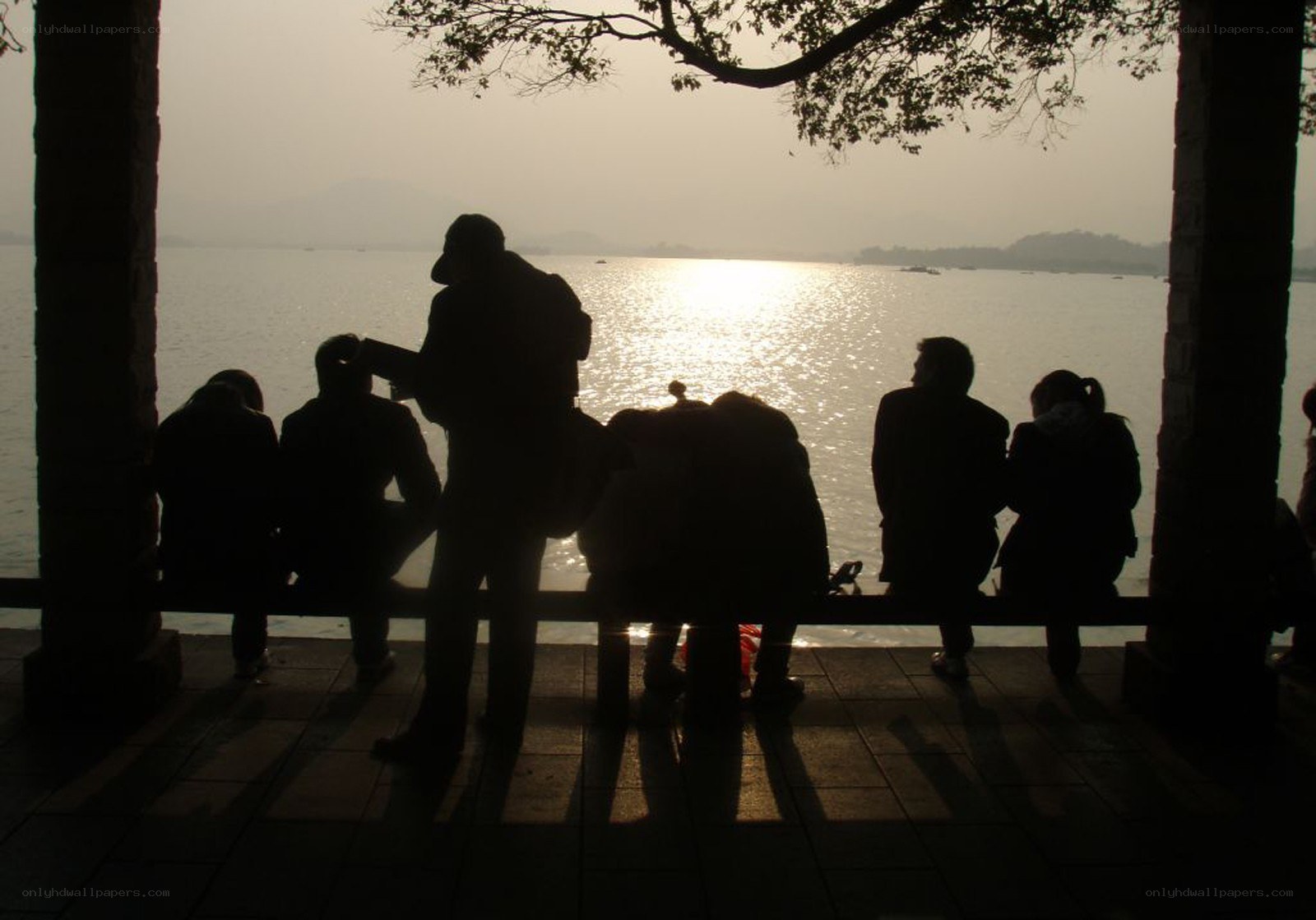 People silhouetted by lake sunset