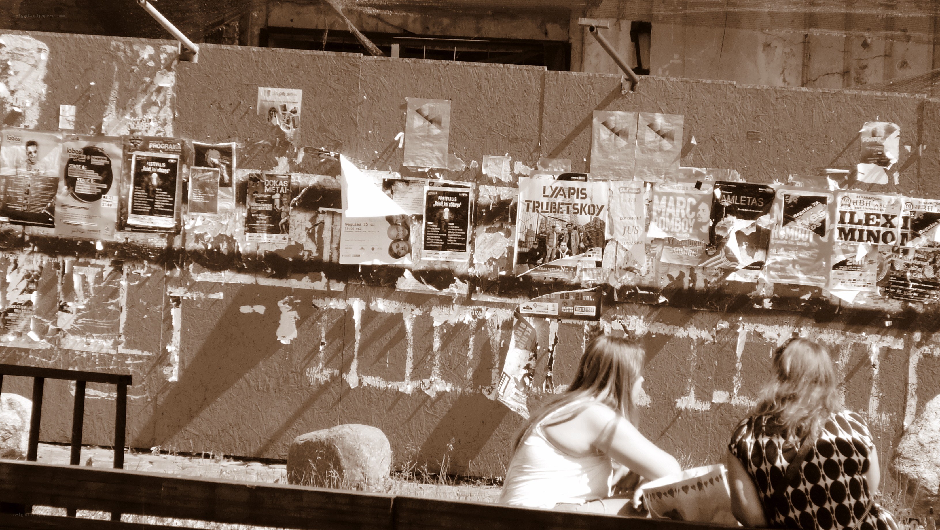 People sitting by a poster-covered wall
