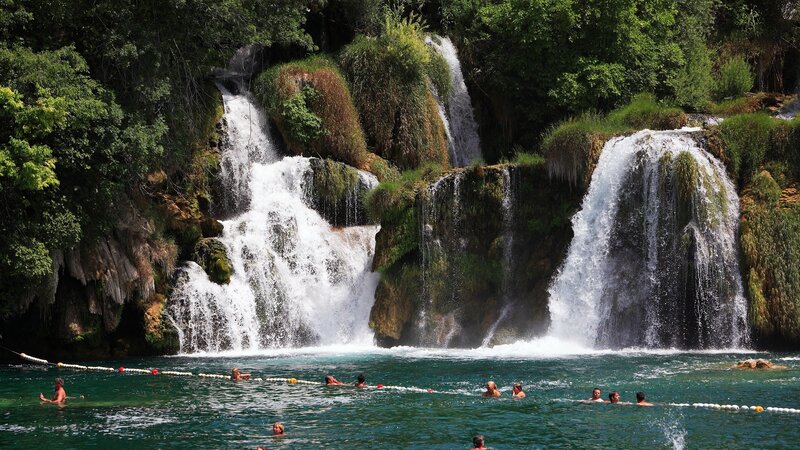 People swimming at a waterfall