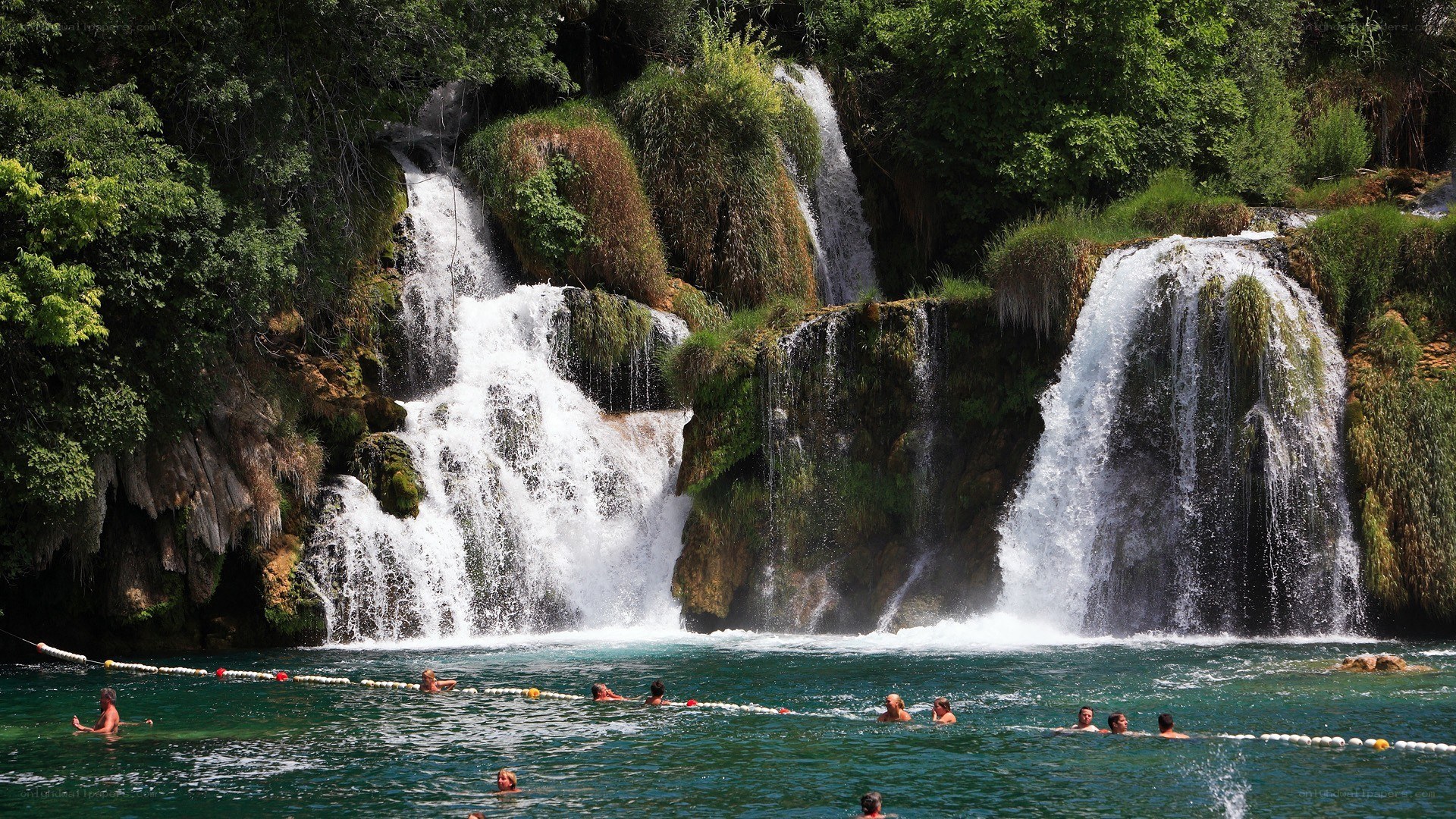 People swimming at a waterfall