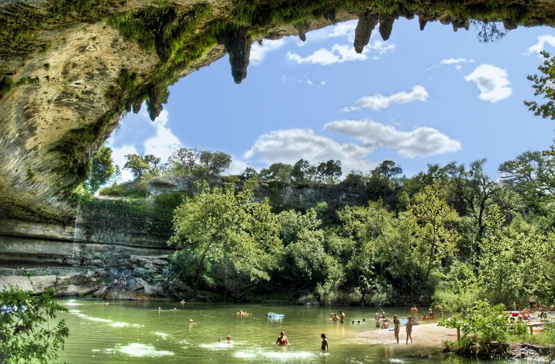 People swimming under a natural rock arch