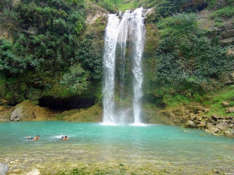 People Swimming under Waterfall