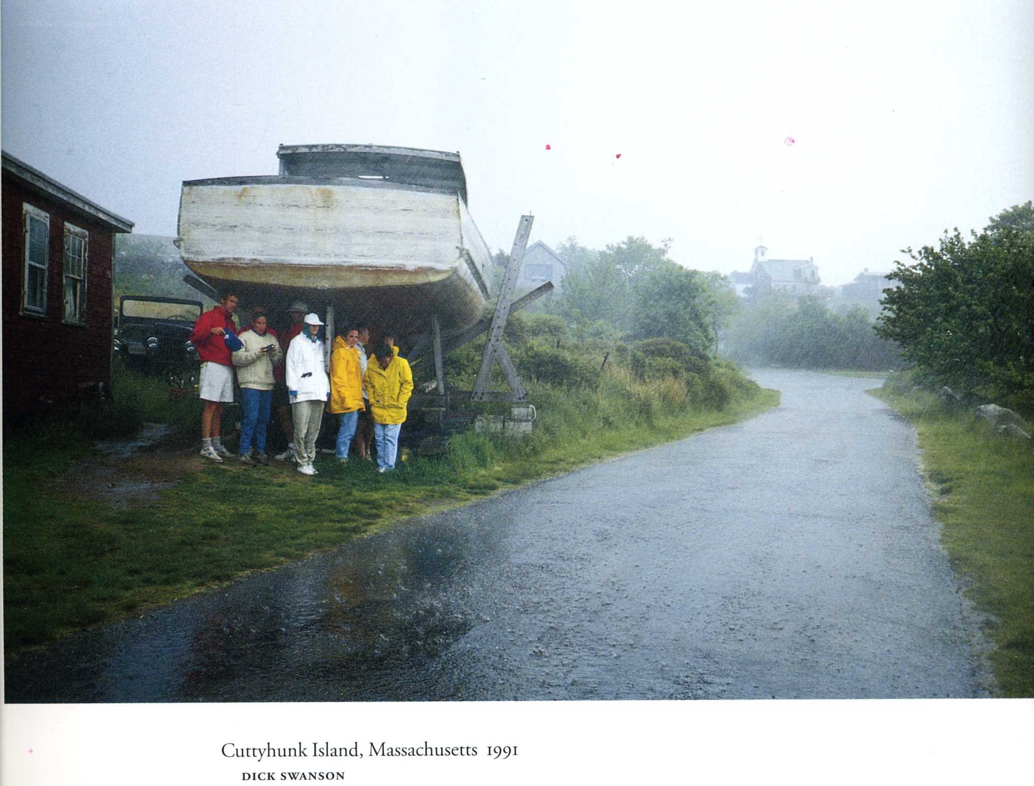 People under a boat in rain