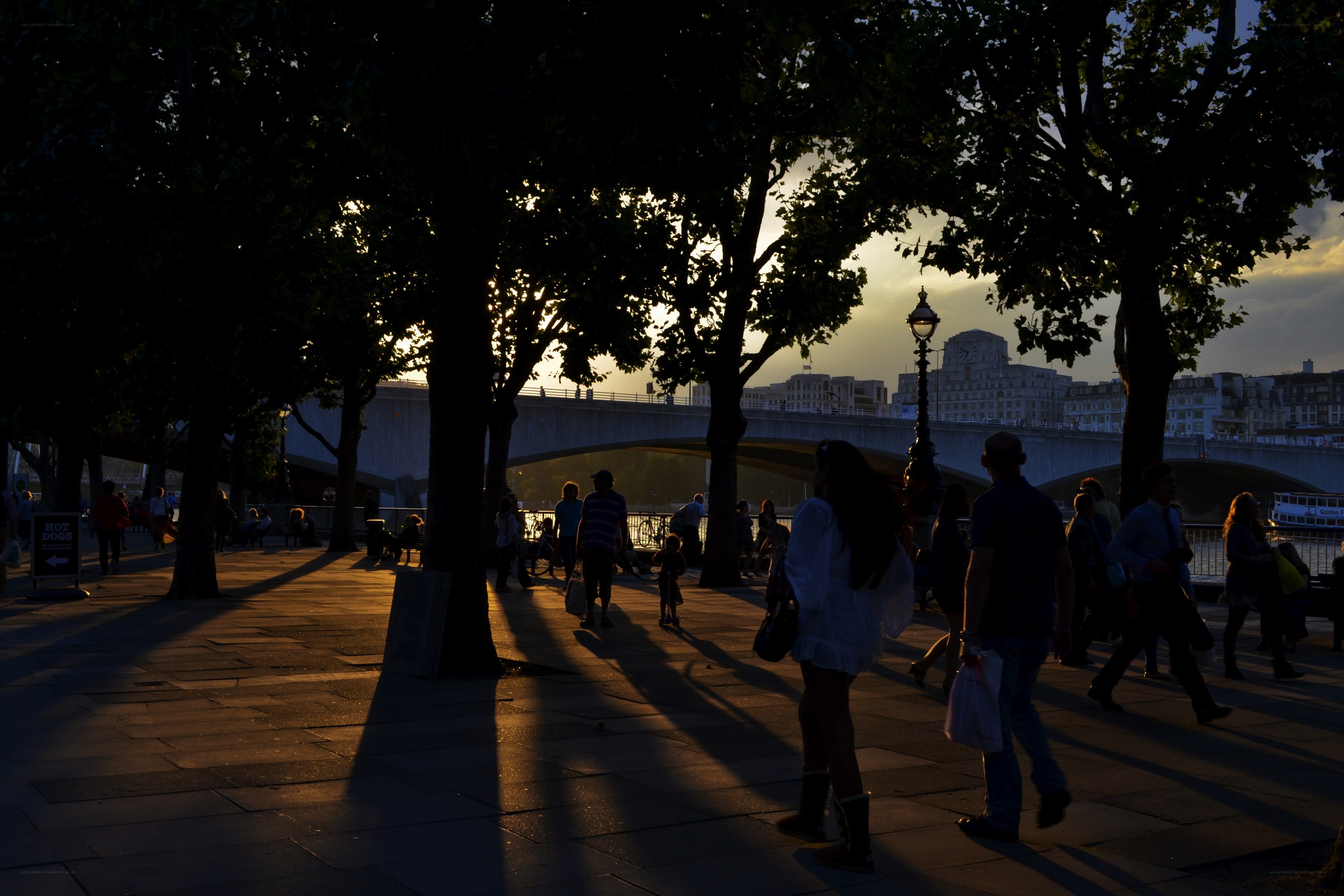 People walking by the river at sunset