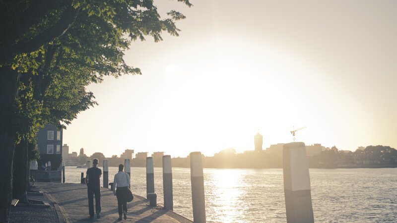 People walking by the water at sunset