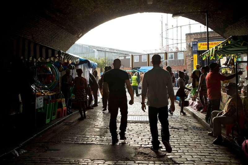 People walking through a market under an arch