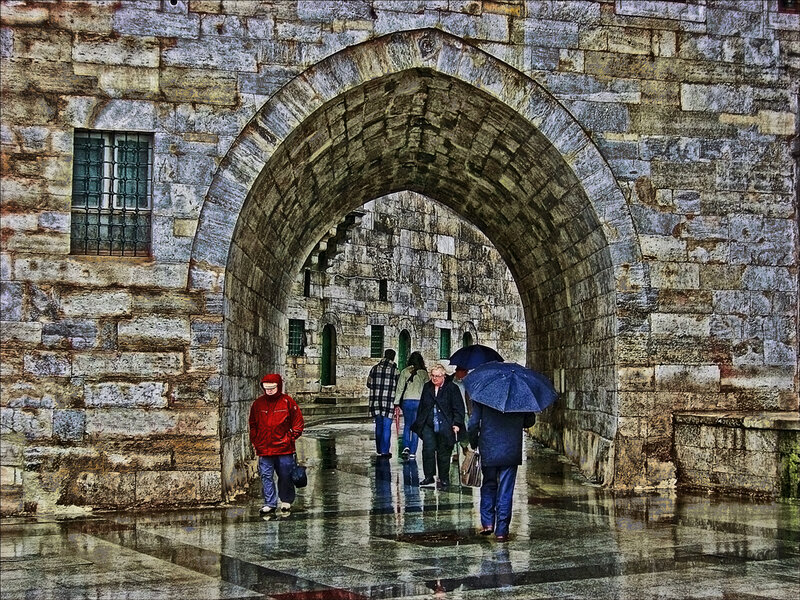 People walking under a stone arch
