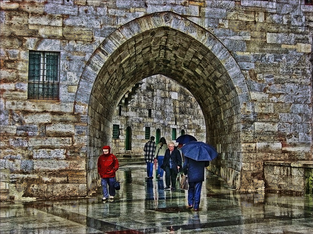 People walking under a stone arch