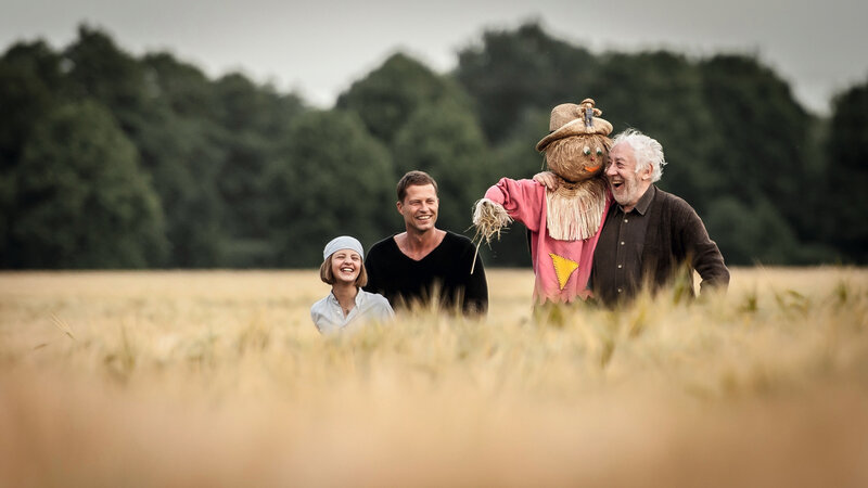 People with Scarecrow in Field