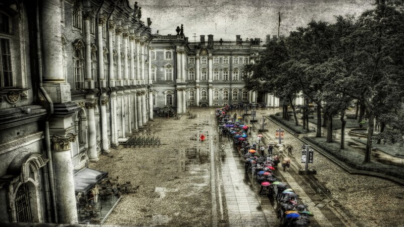 People with Umbrellas in Courtyard