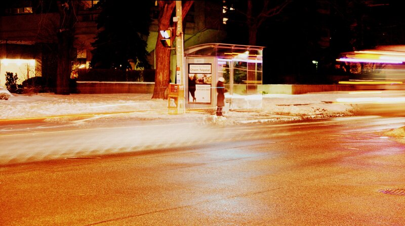 Person at Bus Stop — Orange, Nocturnal