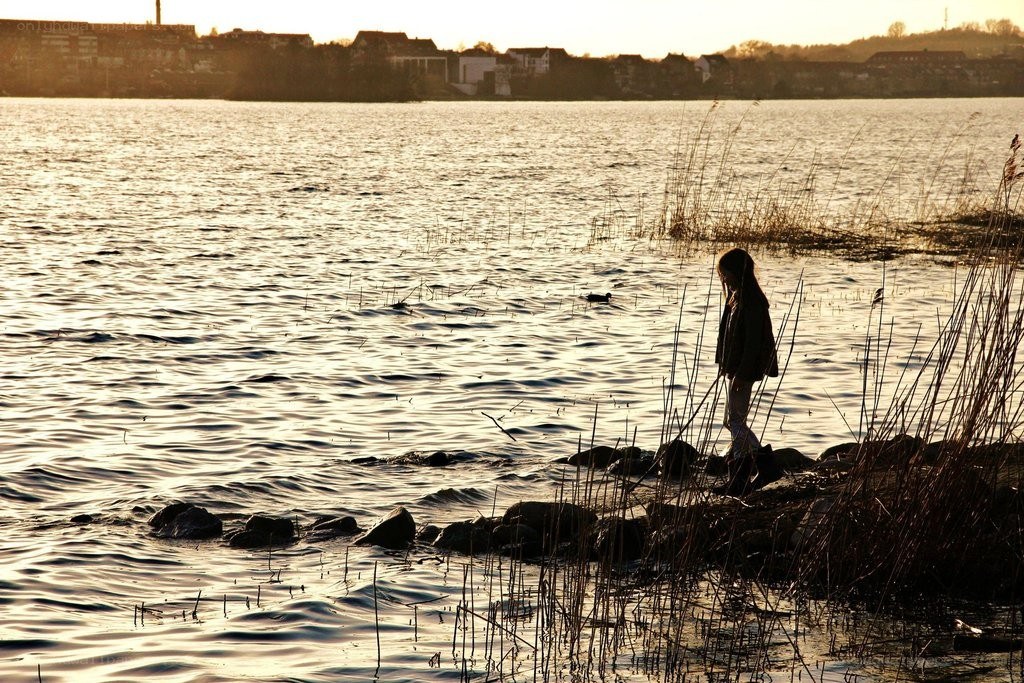 person at lakeside during sunset
