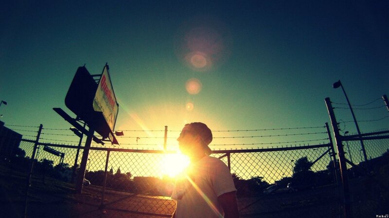person at sunset behind fence