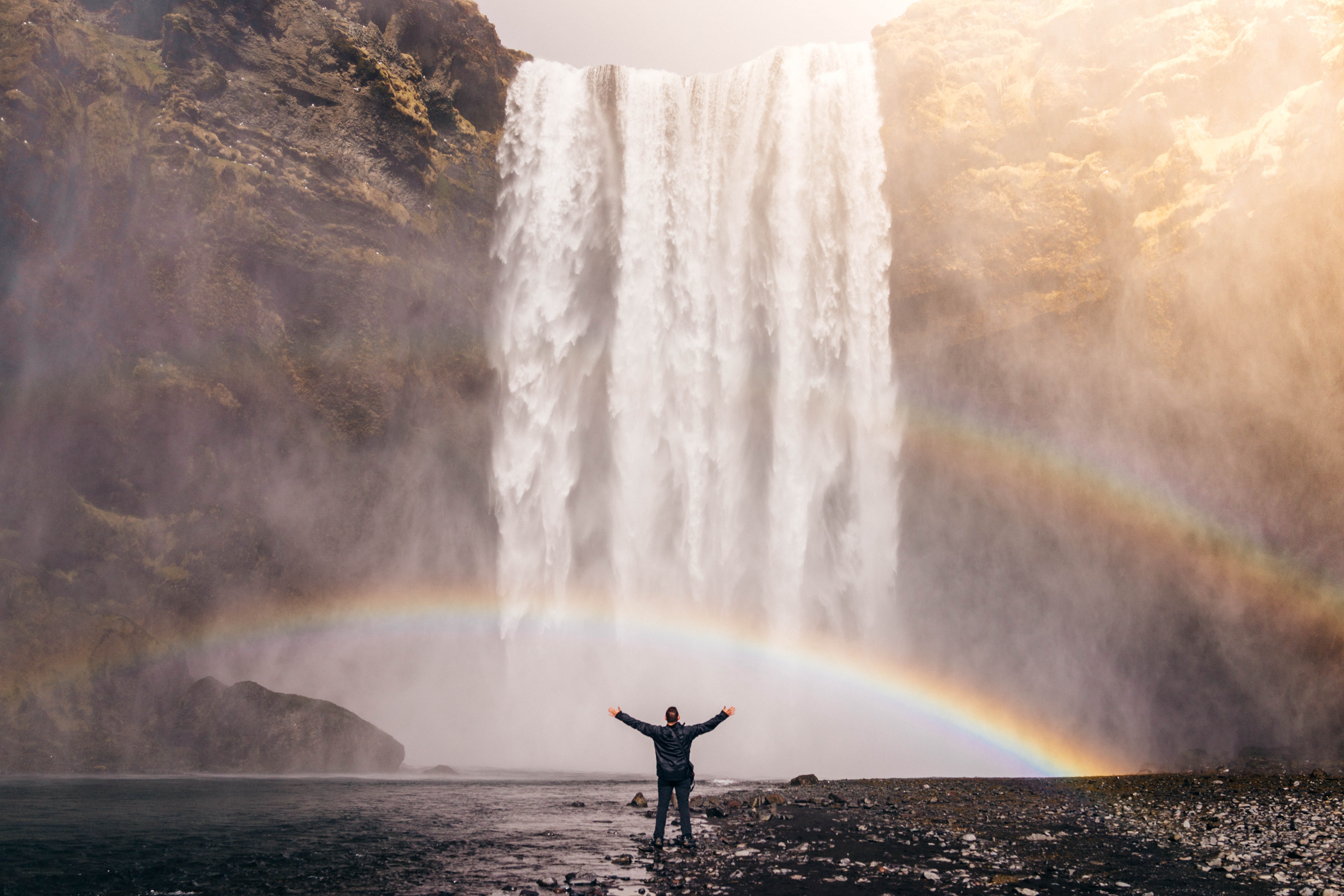 Person at waterfall with rainbow