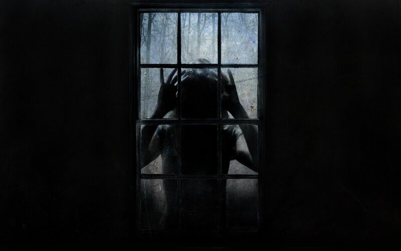 person at window in dark room