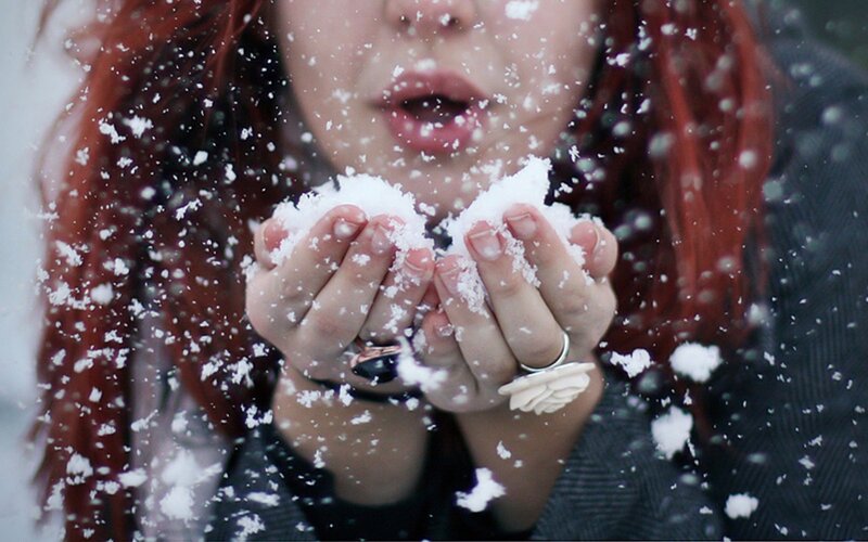 person blowing snow from hands