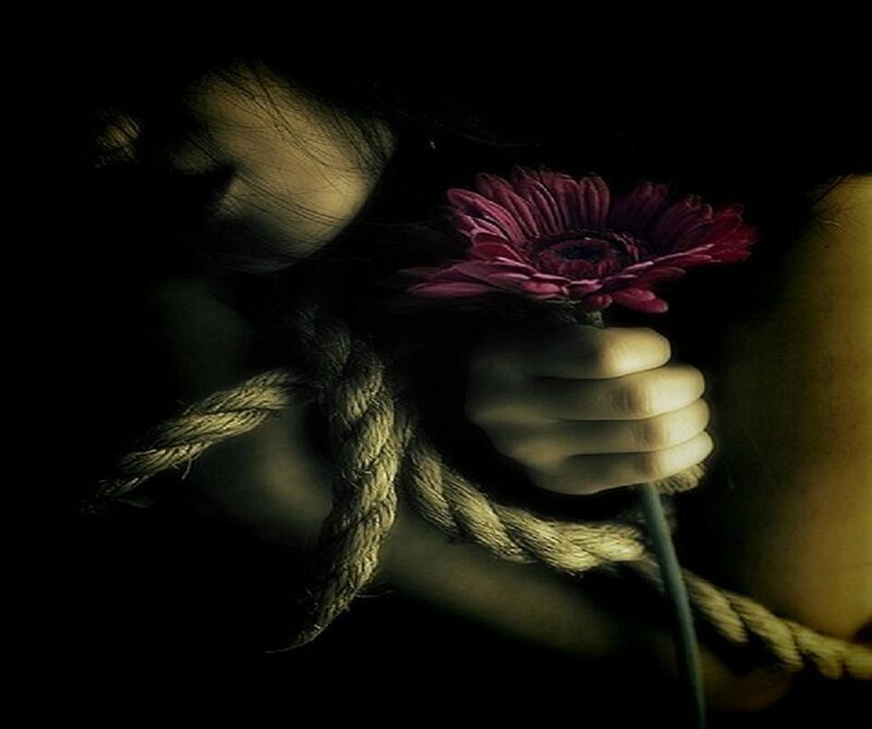 person bound with rope holding flower