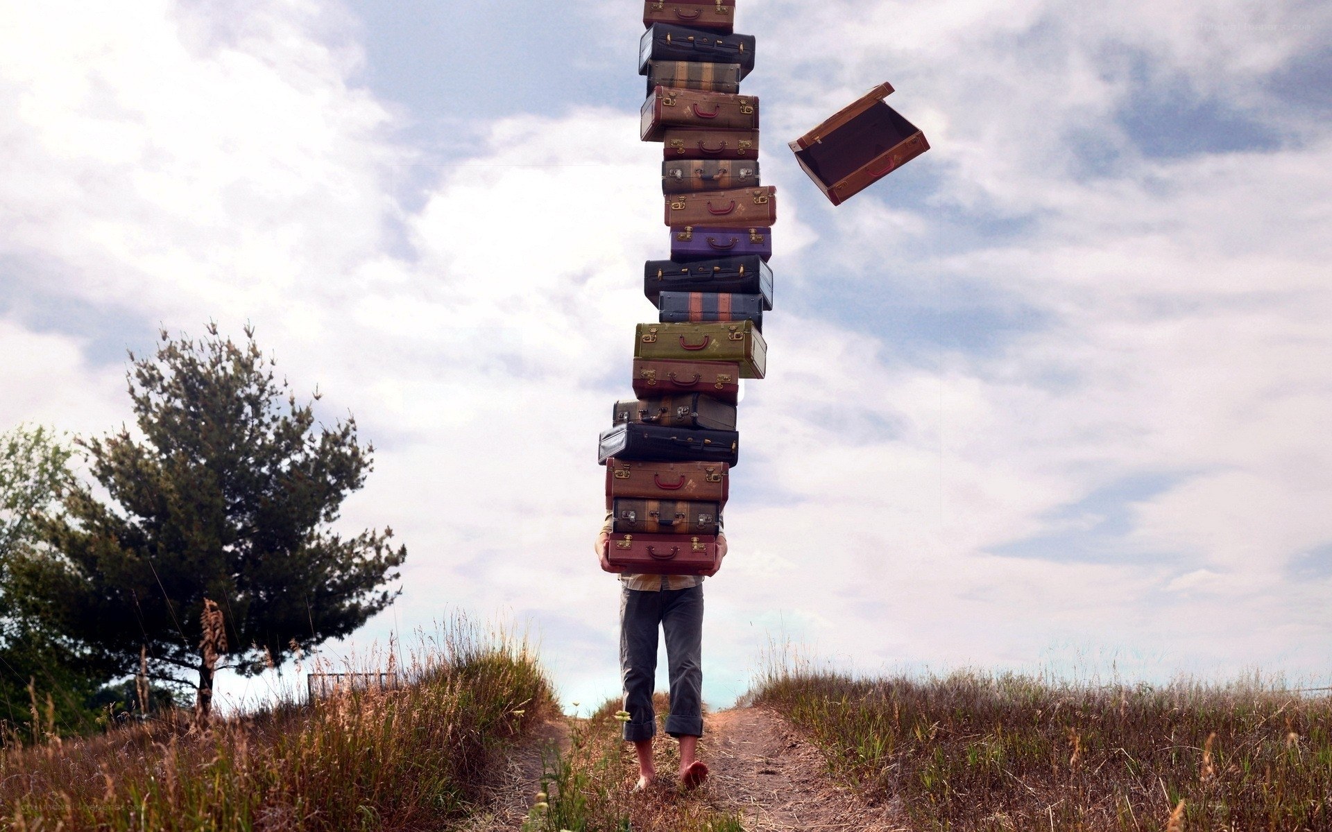 Person carrying a stack of suitcases