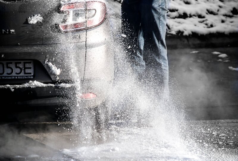 person clearing snow from car