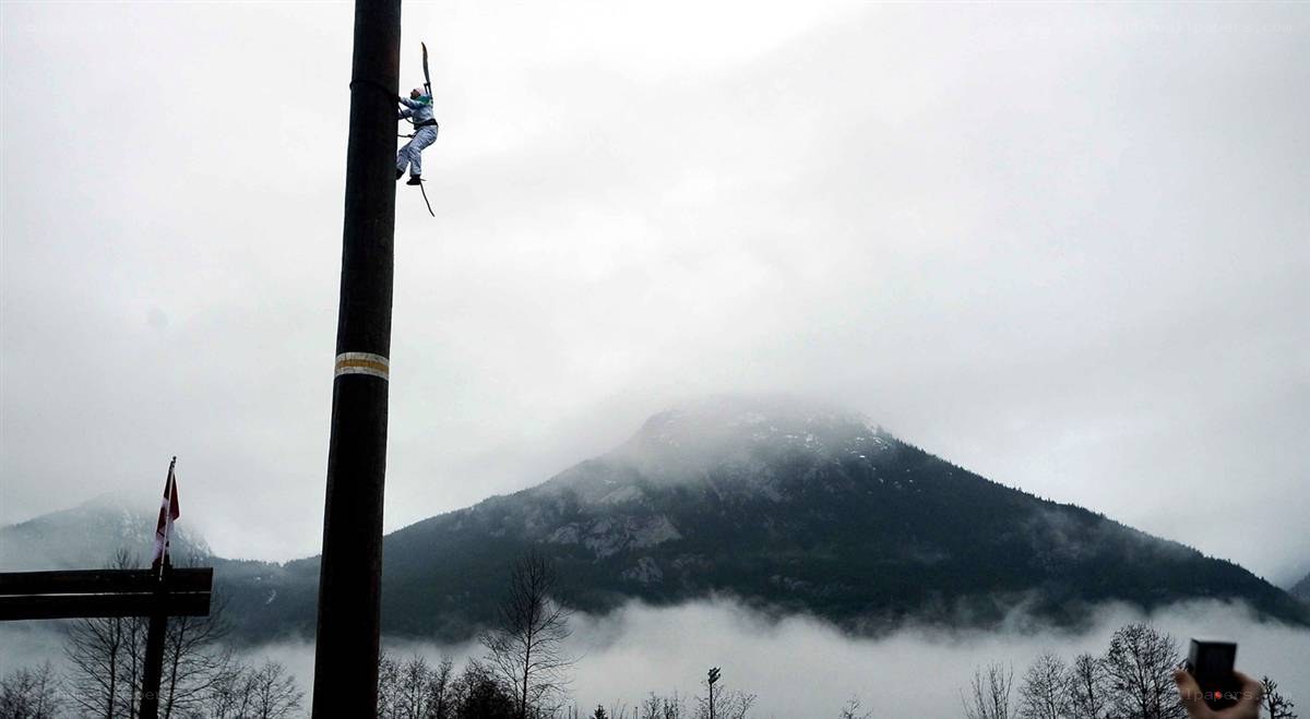Person climbing a pole with mountains