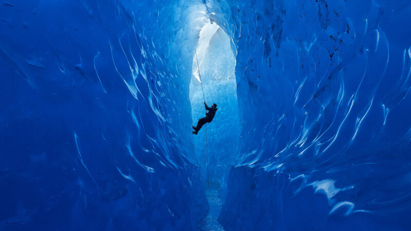 Person Climbing Ice Cave — Blue