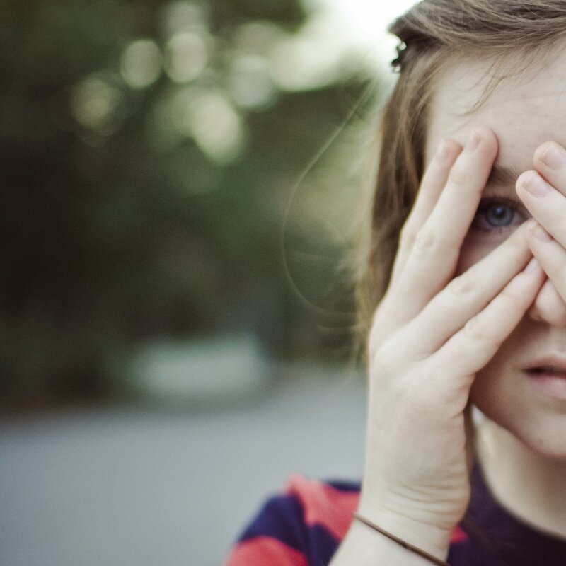 person covering eyes outdoors