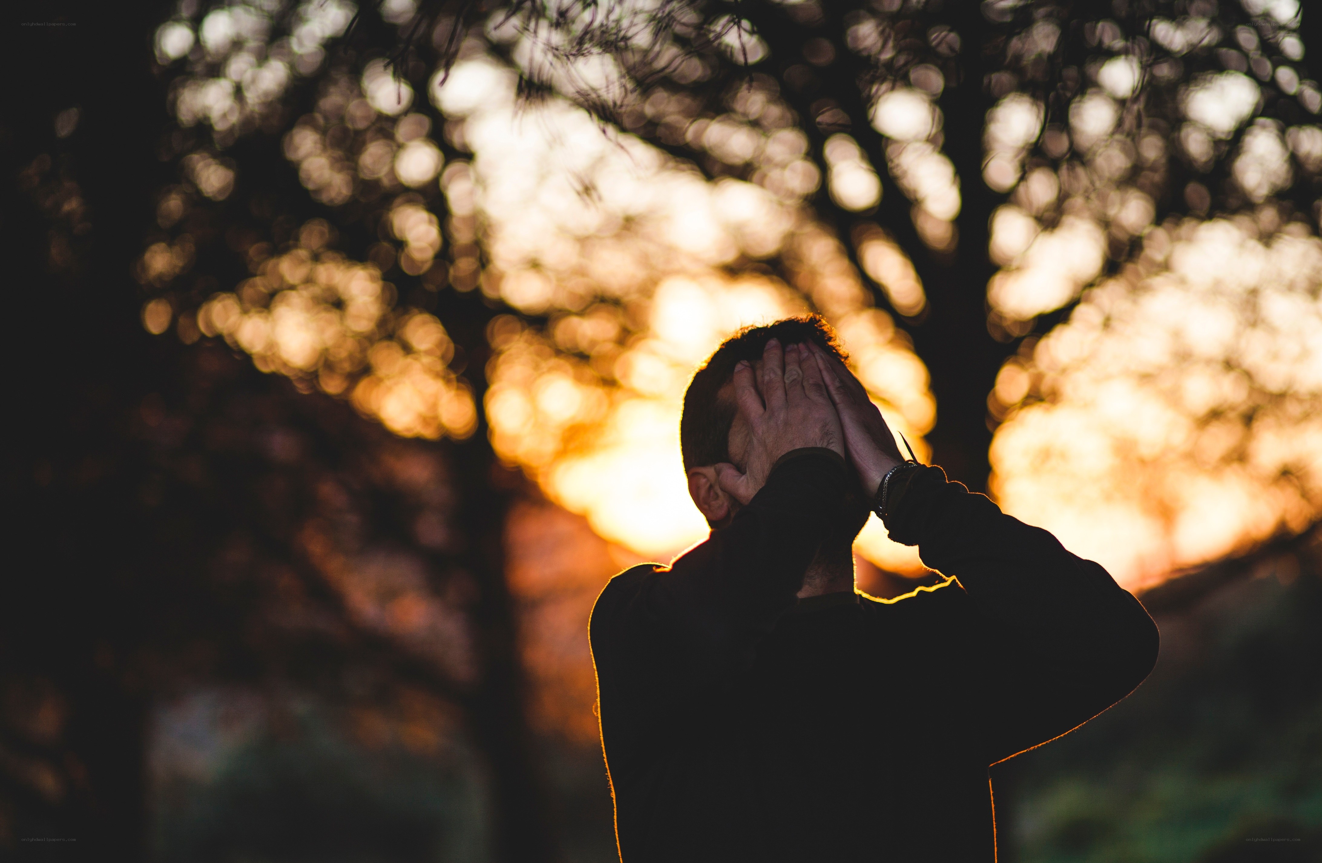 person covering face at sunset