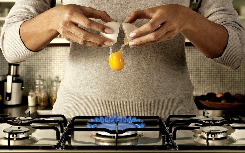person cracking egg on stove