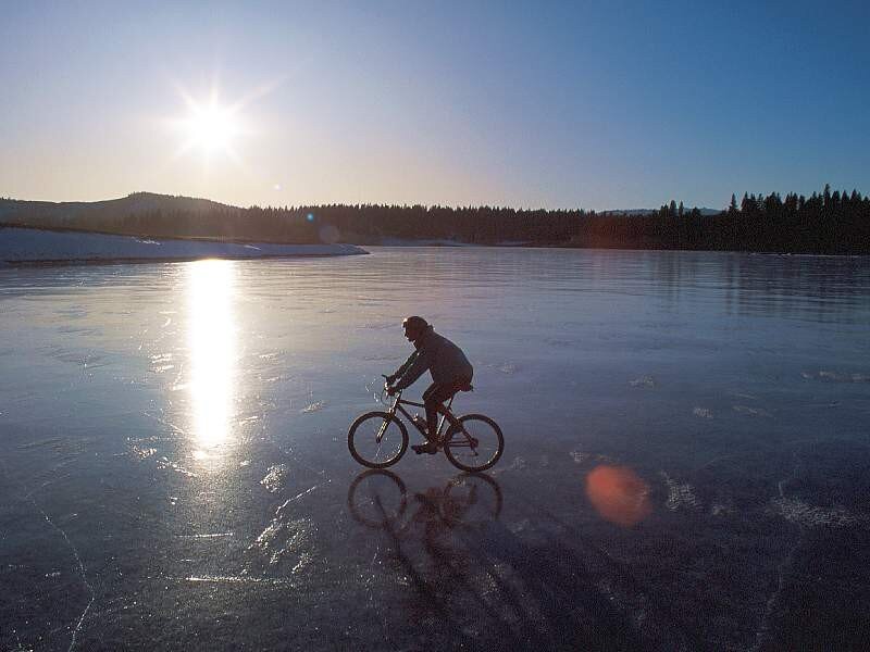 person cycling on frozen lake