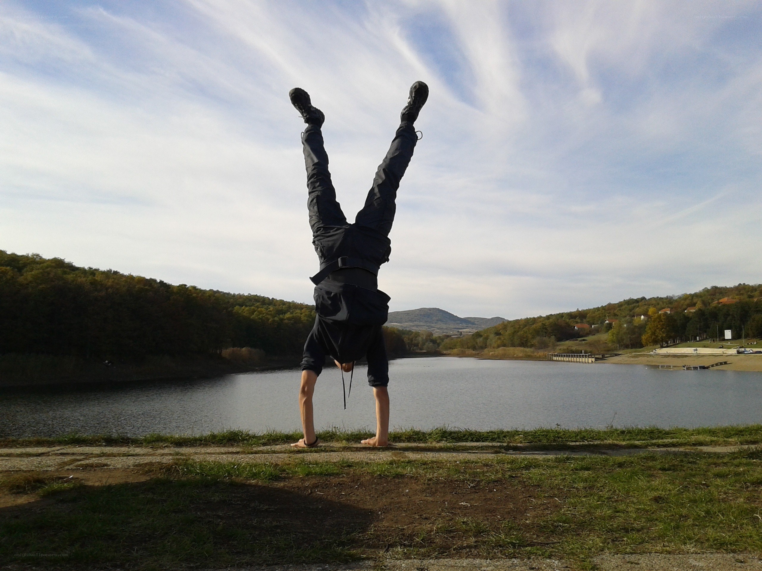 Person doing handstand by lake