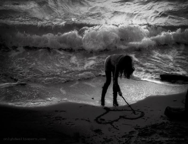 person drawing heart on beach