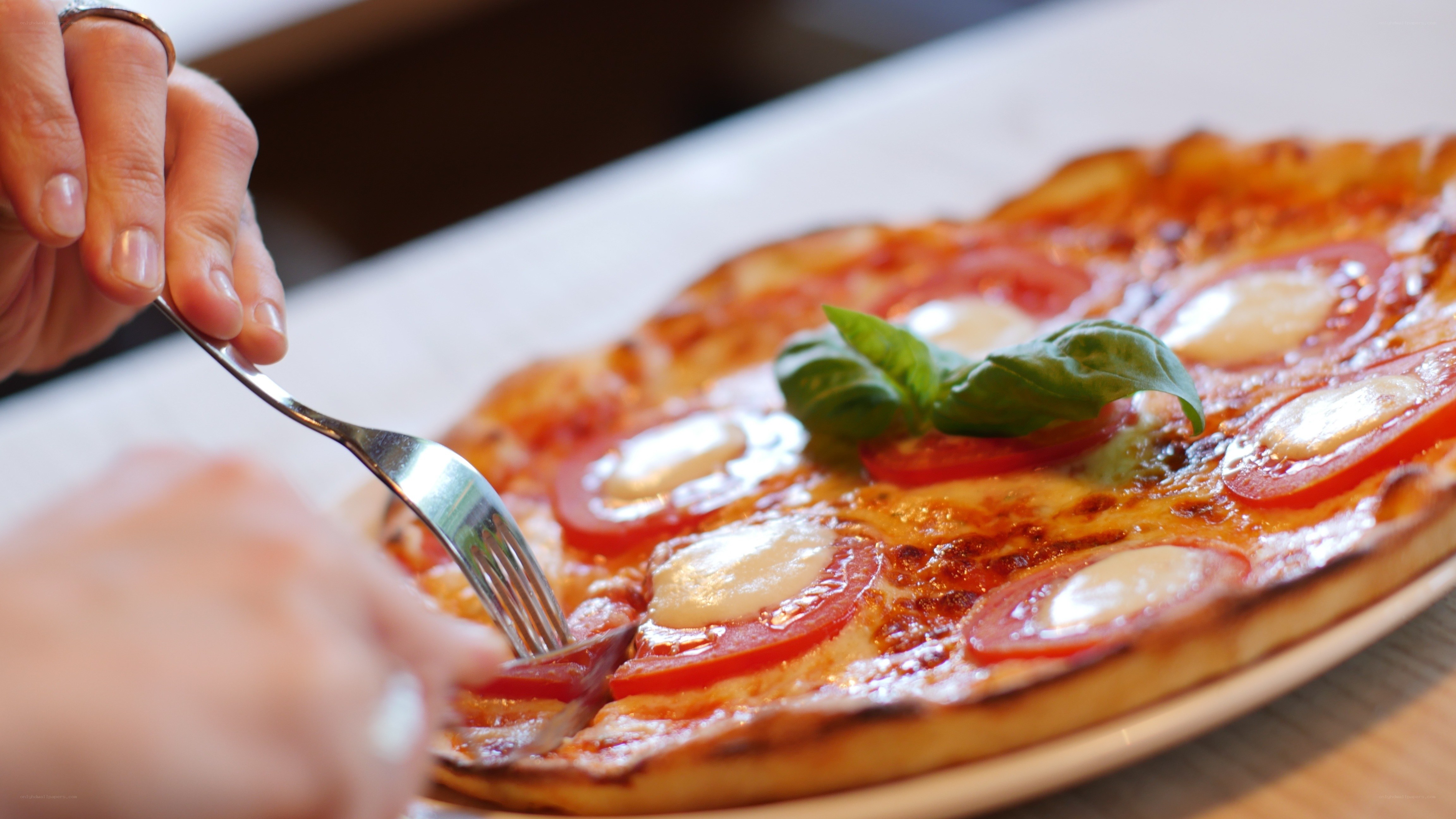 person eating pizza with basil