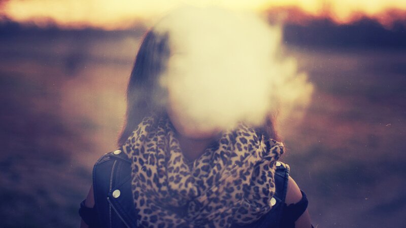 person exhaling vapor at sunset
