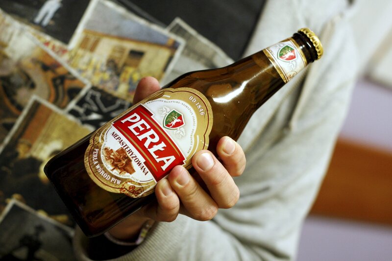 Person holding a Perła beer bottle