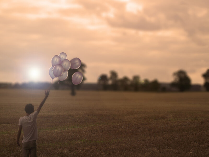 Person Holding Balloons — Brown