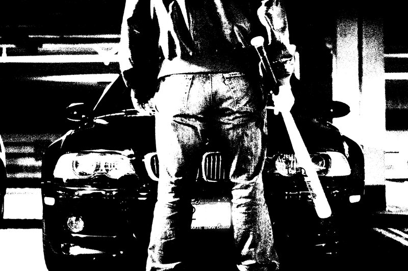 person holding bat near car